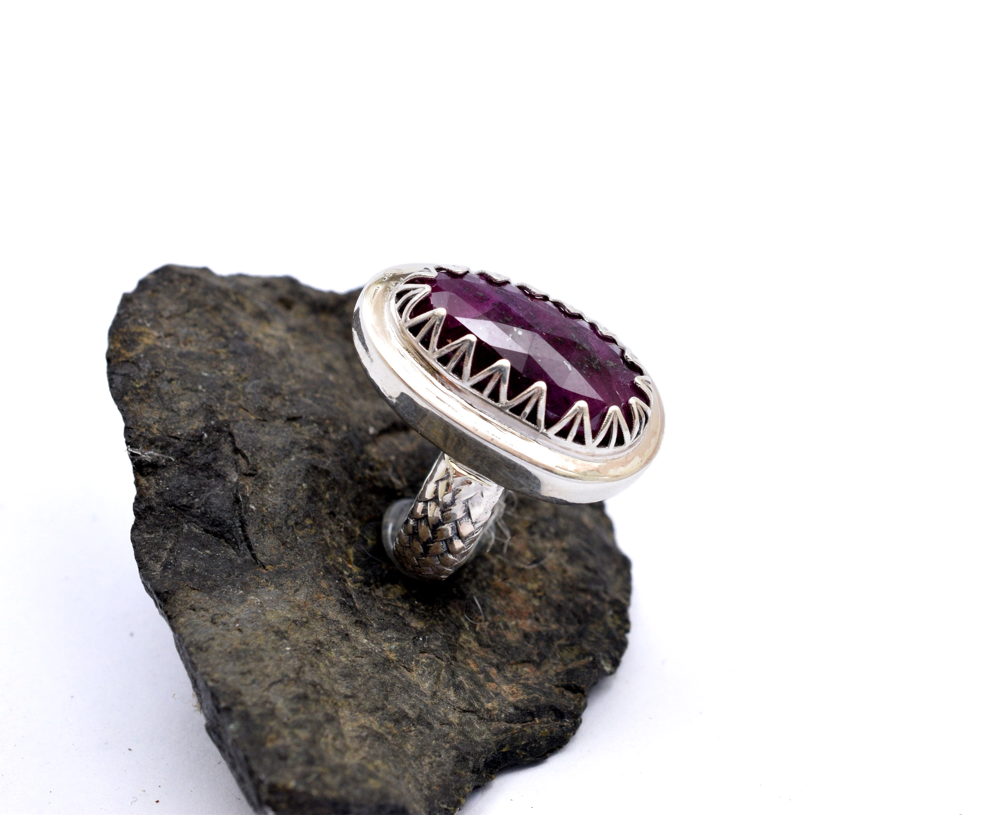 Scalloped sertting of oval ruby gemstone set on a textured silver band