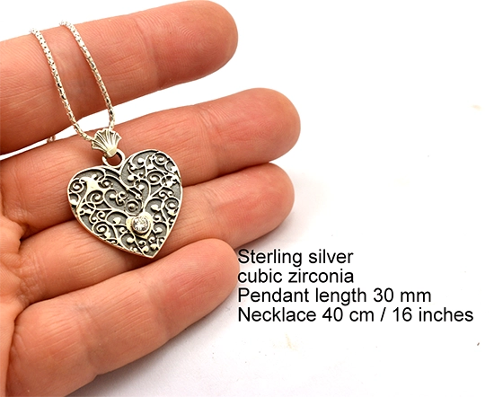 Silver filigree heart pendant held in hand showing size — 30mm pendant, 40cm chain