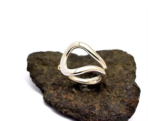 A sculptural 925 silver ring with an open loop silhouette and a single 14k gold ball detail.