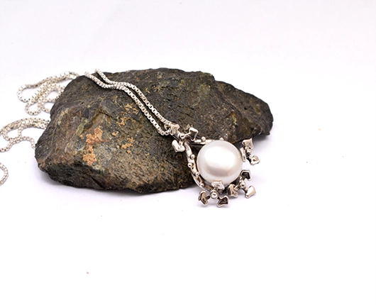 Side view of floral pearl pendant showing depth of silver petals and pearl setting