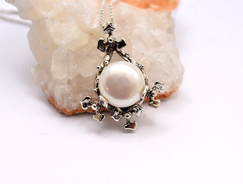 Close-up of botanical openwork filigree sterling silver pendant surrounding freshwater pearl