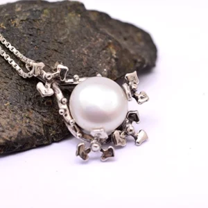Side view of floral pearl pendant showing depth of silver petals and pearl setting